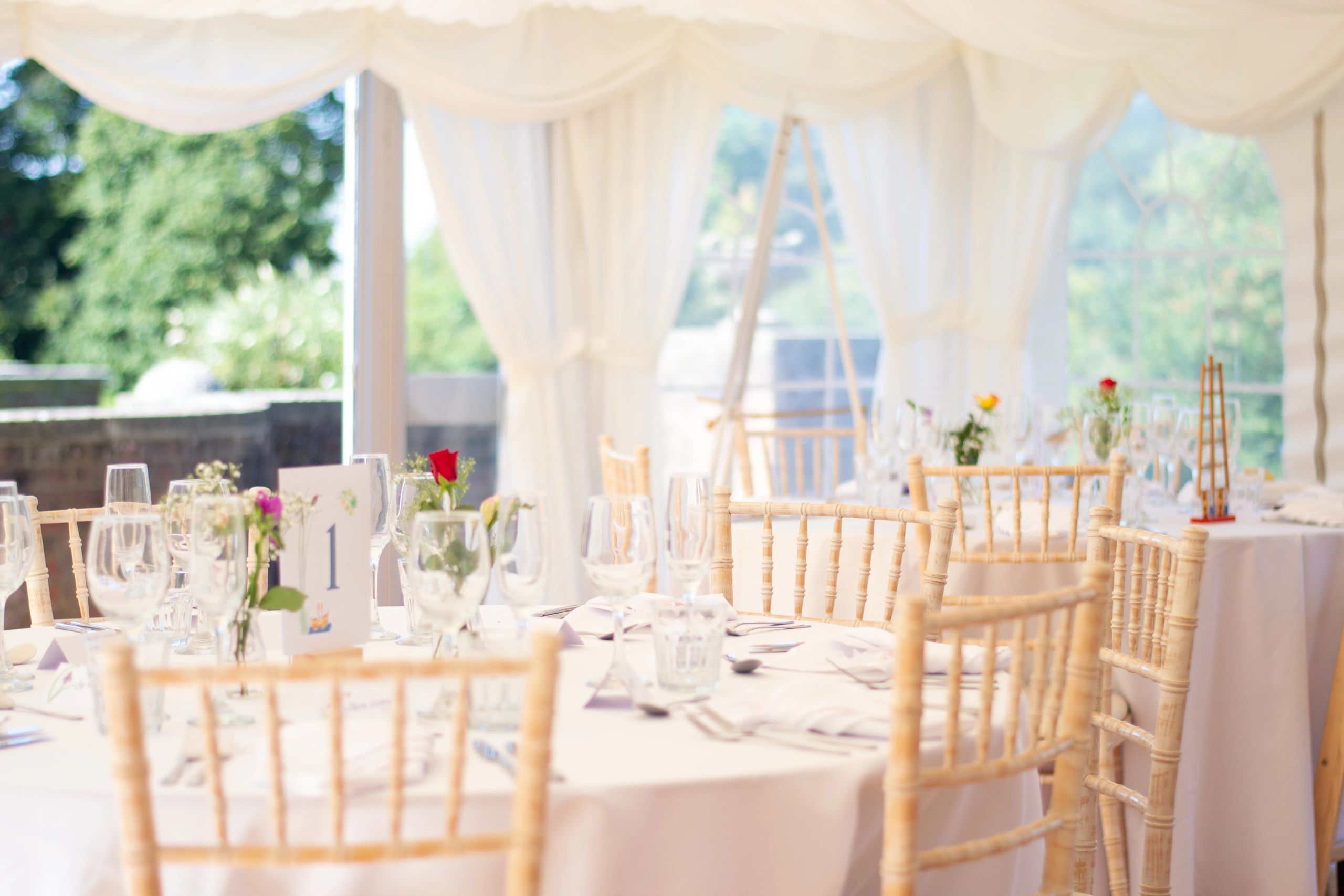 Wedding reception tables and chairs arranged inside a marquee